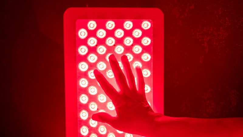 Closeup of hand touching Red Light Therapy Panel LEDs